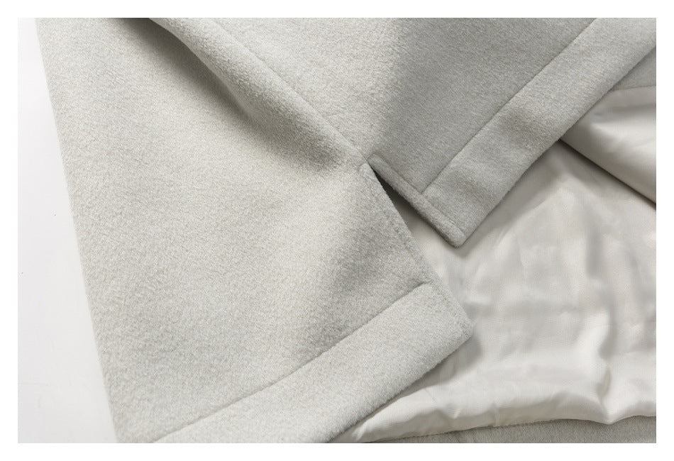 Close-up of an off-white coat hem, sleeve cuff, and a glimpse of the light lining.