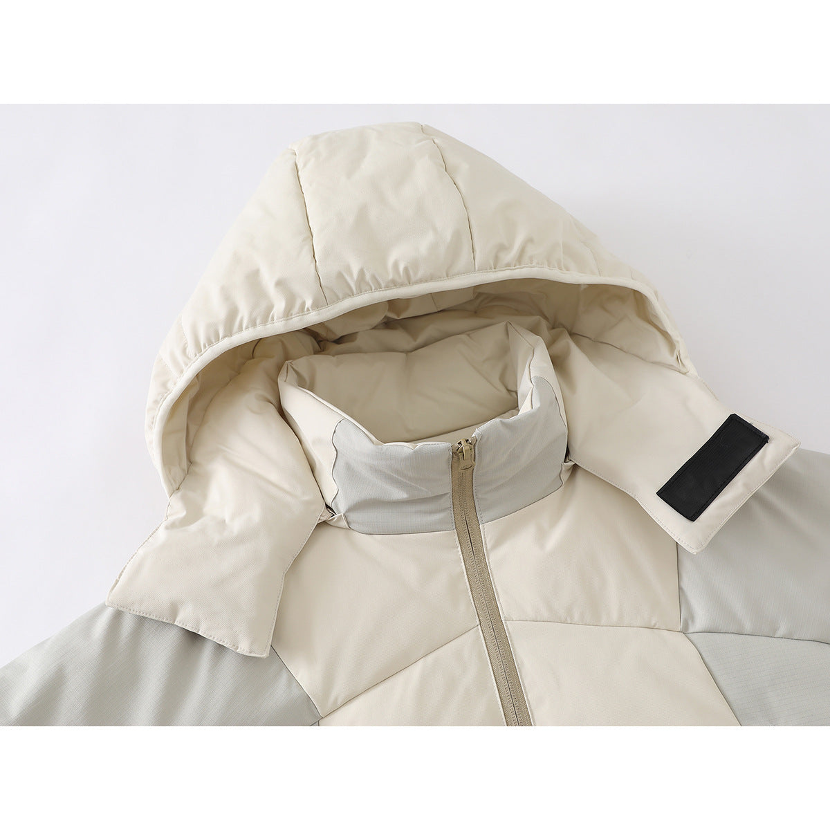 Close-up of an off-white jacket's padded hood, high zip collar, and black rectangular patch.