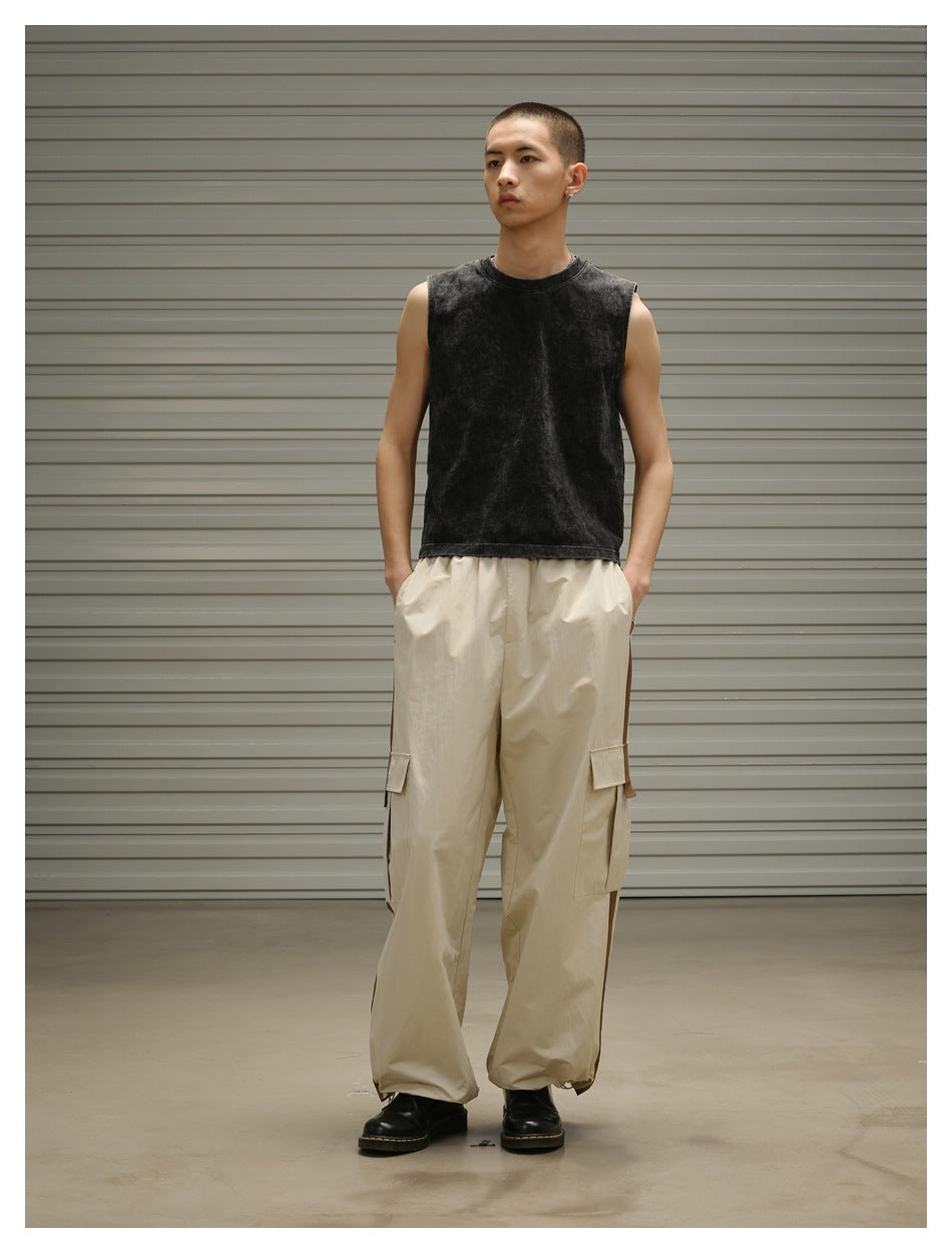 Front view of a model wearing a black sleeveless top and loose beige cargo pants with side pockets.