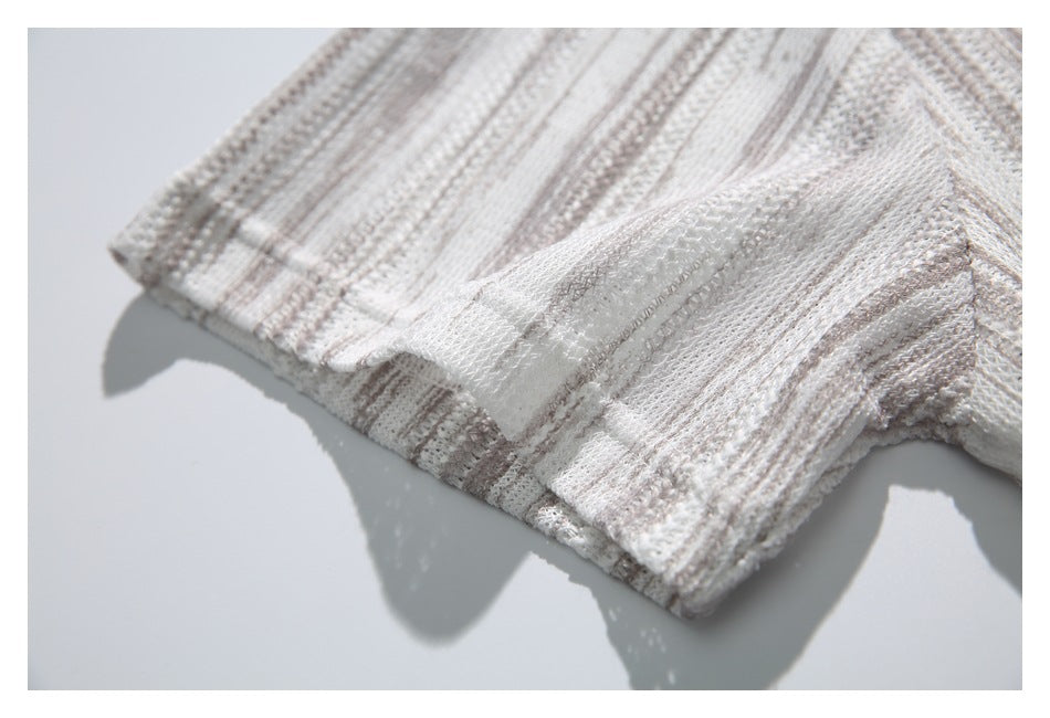Close-up of the striped openwork knit and finished cuff on an ivory polo shirt sleeve.