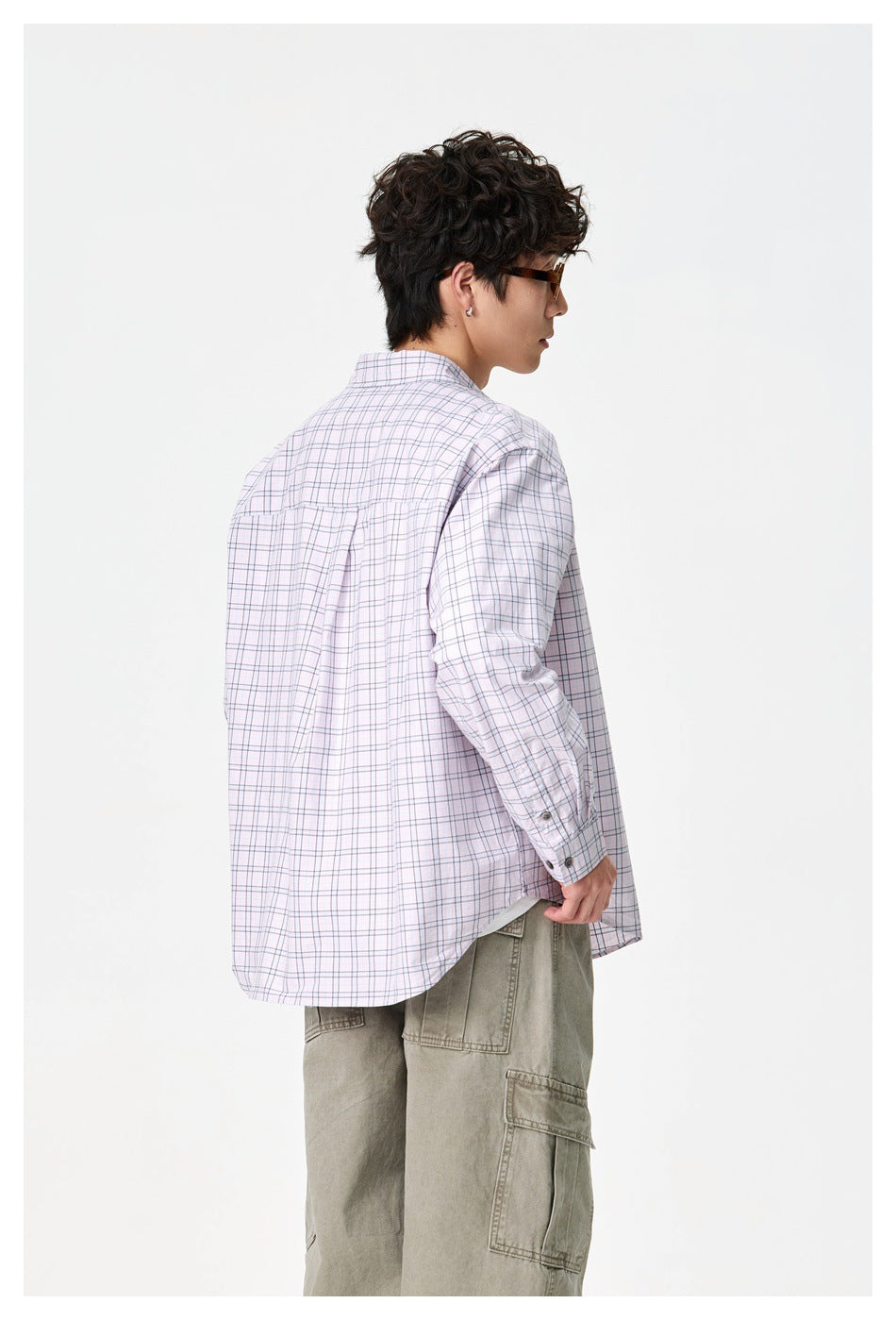 Model shown from behind wearing an oversized pale pink plaid button-up shirt with long sleeves.