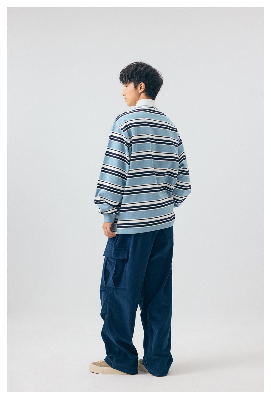 Back view of a person in a blue, navy and white striped long-sleeve polo top and navy cargo pants