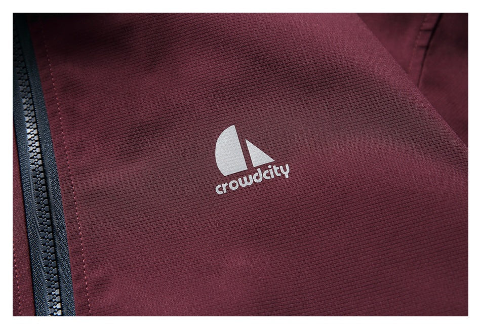 Close-up of the jacket’s white chest logo on burgundy fabric beside the black center zipper.