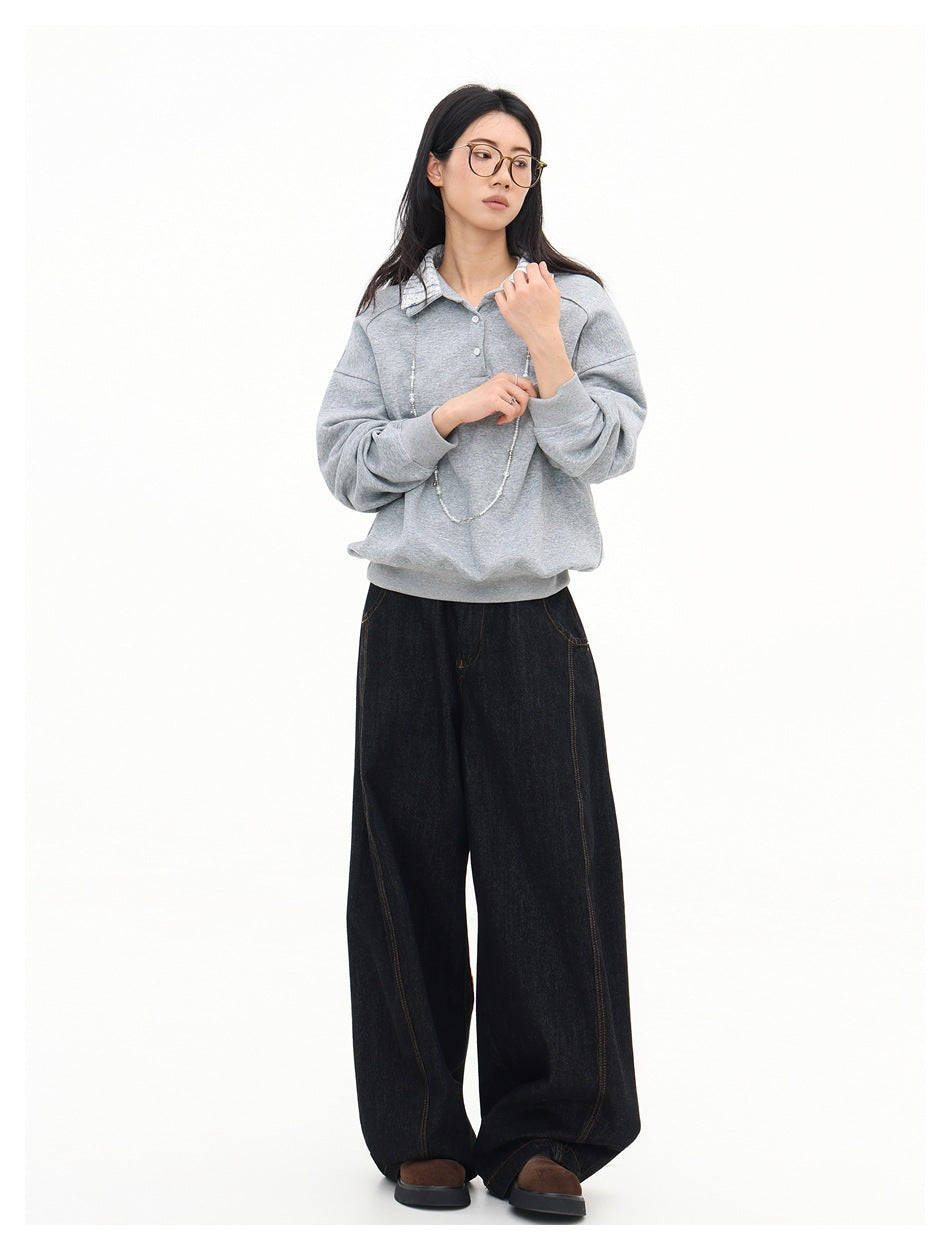 Model wearing a light gray pullover with a patterned collar and button placket, paired with wide-leg black jeans.
