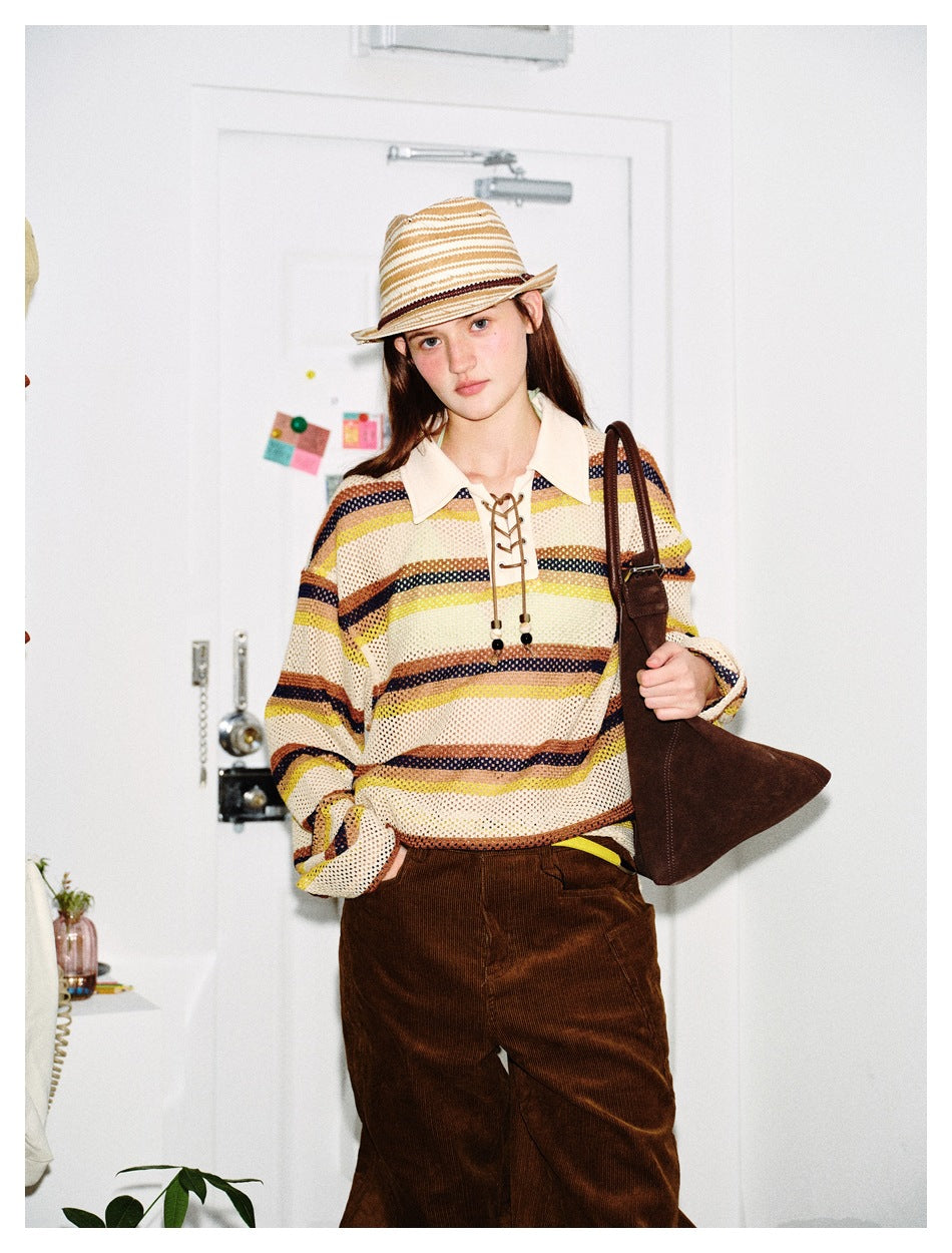 Model wearing a cream open-knit rugby shirt with yellow, brown and navy stripes, pointed collar and lace-up neckline.