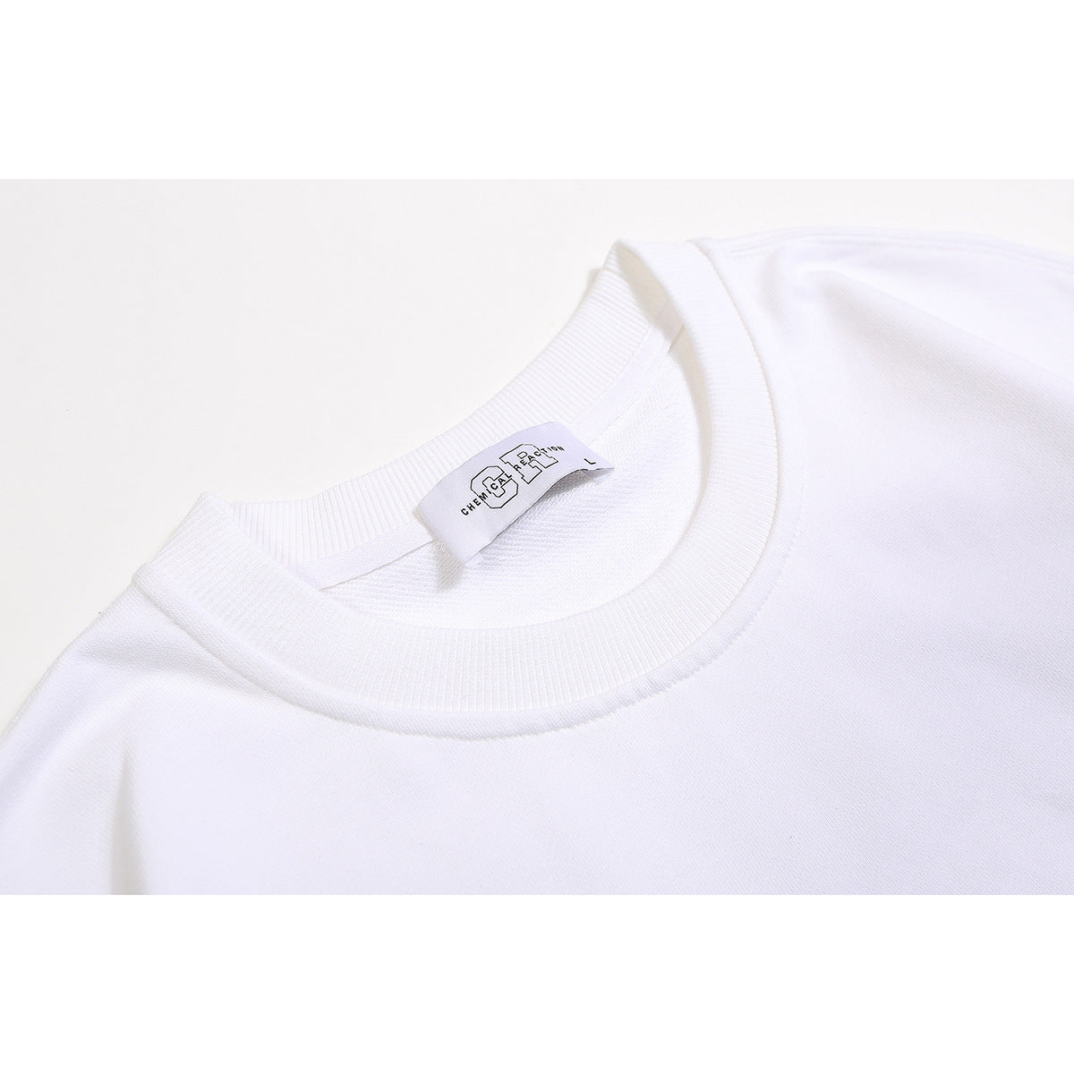 Close-up of a white crewneck sweatshirt neckline with ribbed trim and a sewn-in neck label.