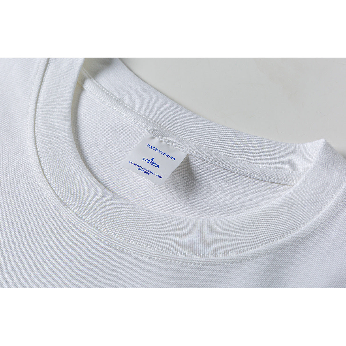 Close-up of a white T-shirt’s ribbed crew neckline and inner label marked “Made in China.”