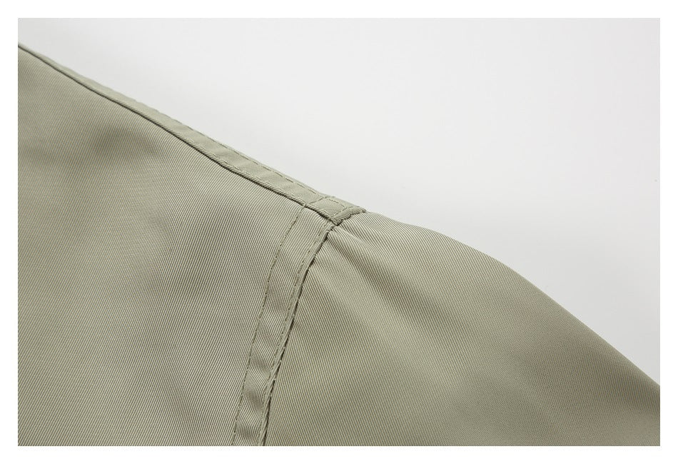 Close-up of an olive-gray garment shoulder seam and sleeve attachment.