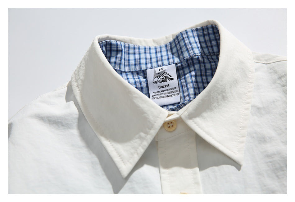 Close-up of the off-white shirt collar and blue checked inner lining, with a sewn neck label.