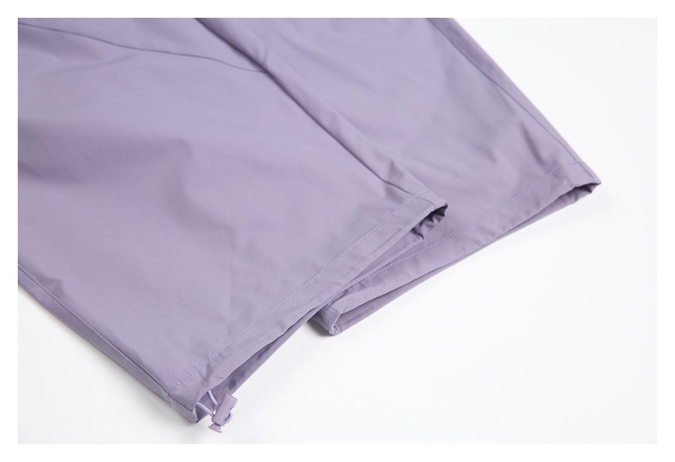 Close-up of the stitched hems of lavender trouser legs, with an adjustable cord at one cuff.