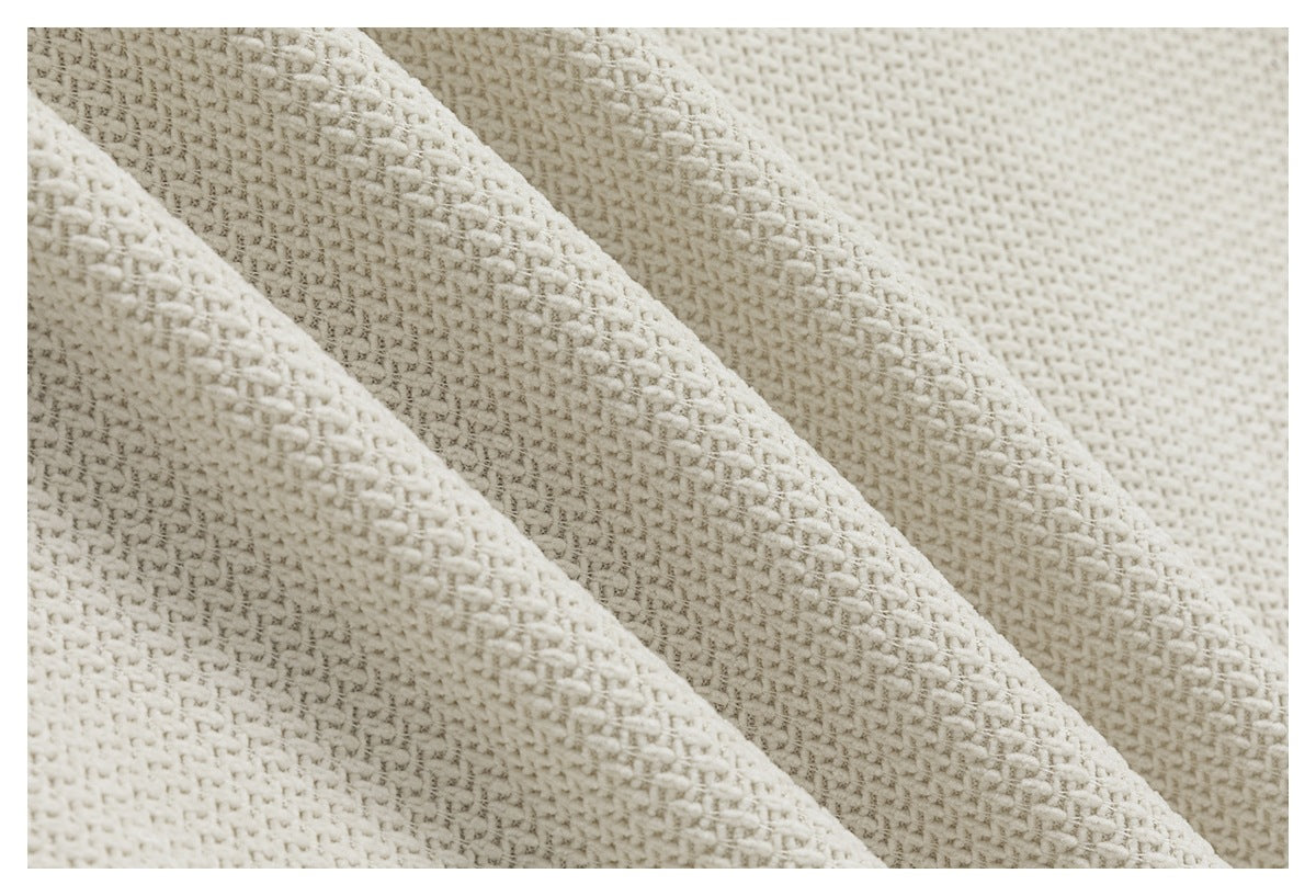 Macro view of the ivory garment's raised woven texture and overlapping fabric folds.