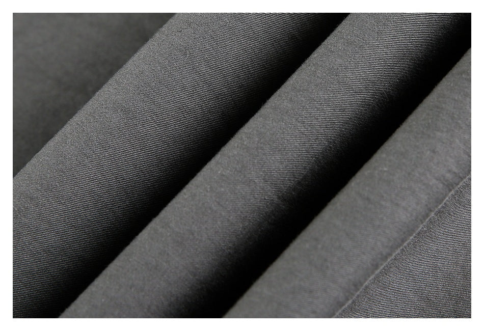 Close-up of dark gray garment fabric arranged in soft folds, showing its fine surface texture.