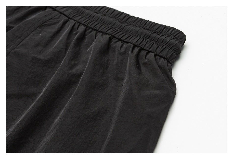 Close-up of black pants showing the gathered elastic waistband and fabric folds.
