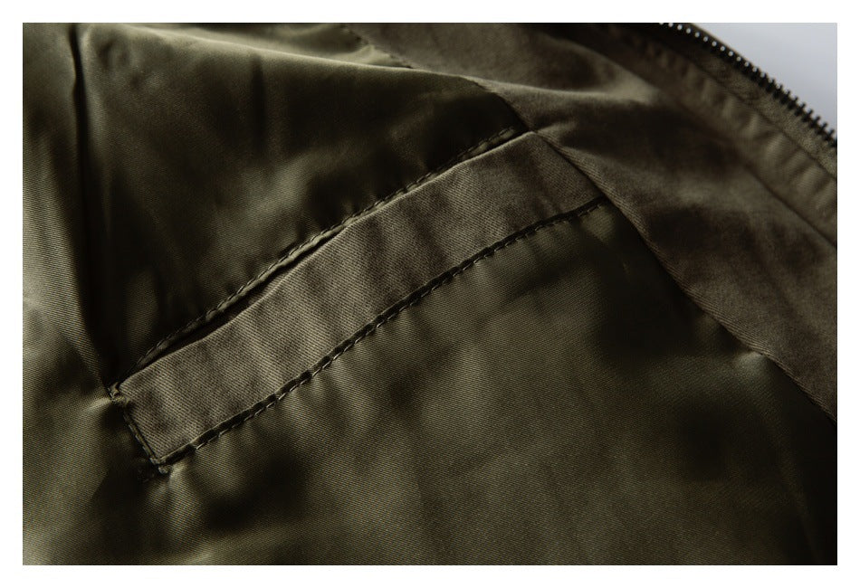 Close-up of a stitched interior pocket on the olive jacket beside the zipper.