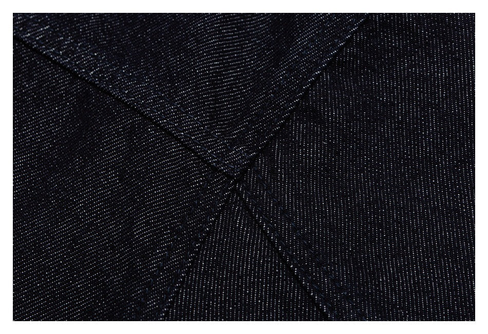 Close-up of intersecting stitched seams on dark indigo denim.