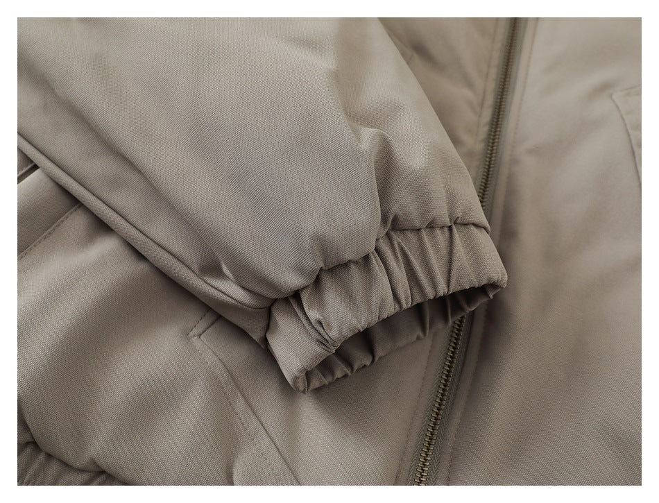 Close-up of a taupe jacket sleeve with a gathered elastic cuff beside the front zipper.
