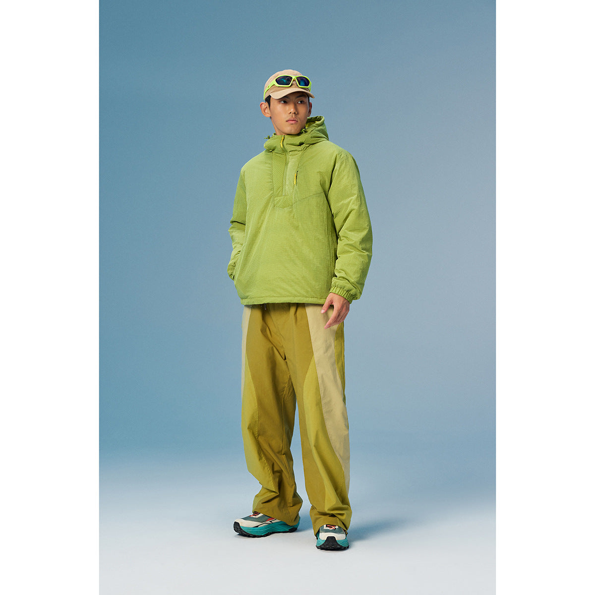 Man models a lime-green hooded pullover with olive color-block pants.