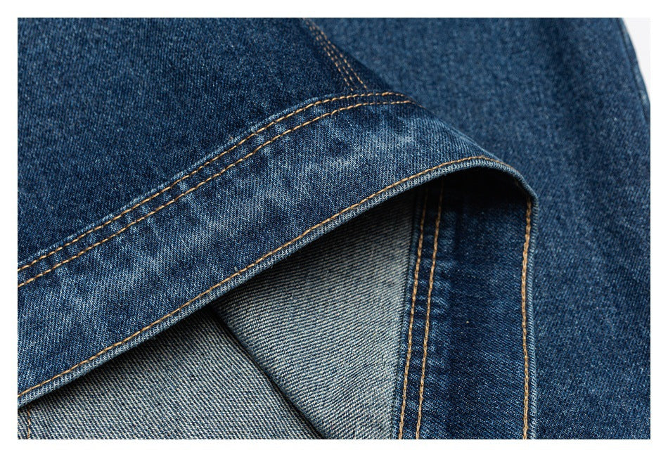 Close-up of folded blue denim showing a stitched edge and lighter reverse side.