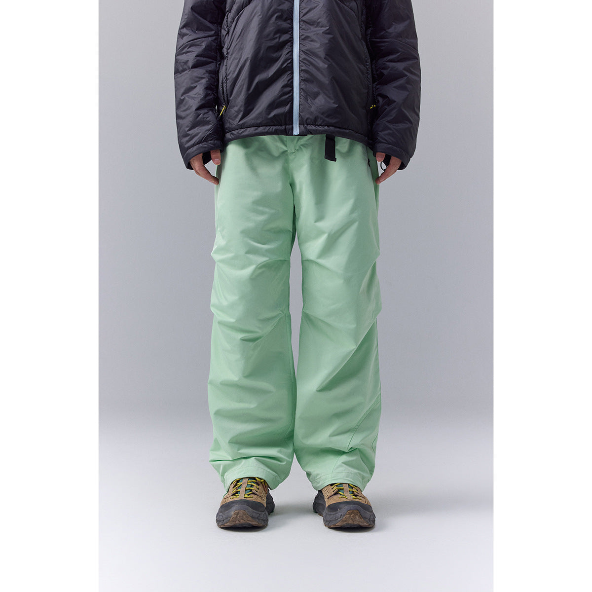 Front view of a person wearing loose mint-green pants with a black jacket.