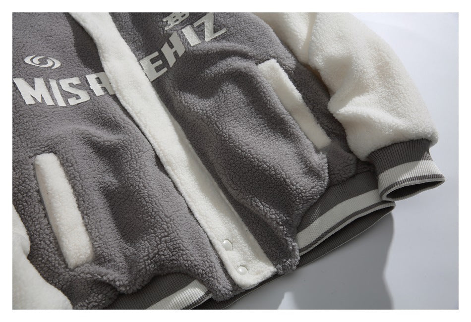 Close-up of a gray and cream sherpa jacket front with white lettering, contrast panels, snap placket, and ribbed trim.