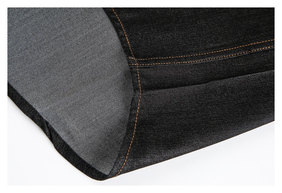 Close-up of a black denim shirt seam showing the reverse side of the fabric and tan stitching.