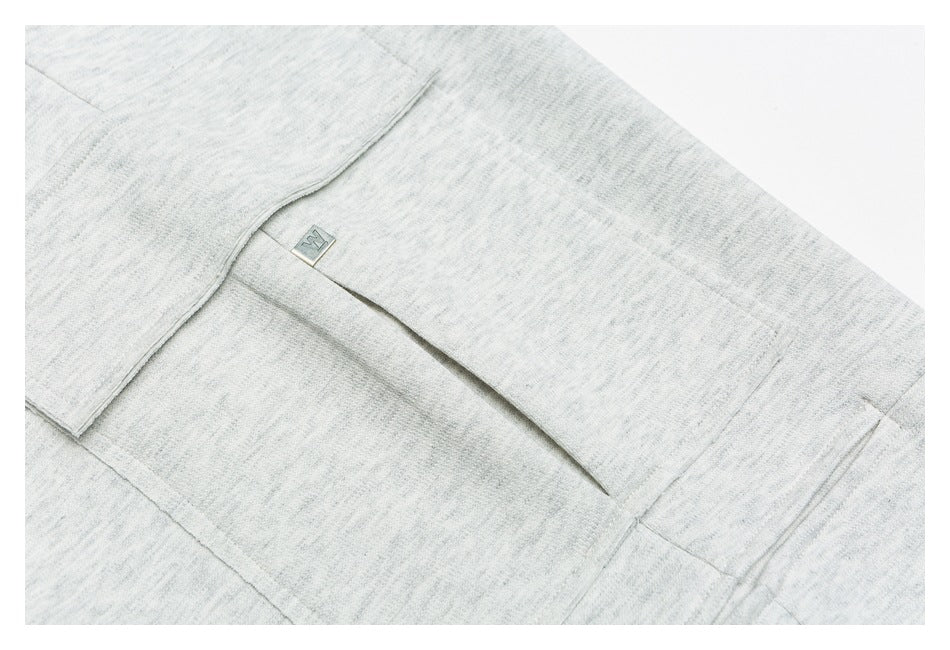 Close-up of a gray cargo pocket with a flap and small metal garment tab.