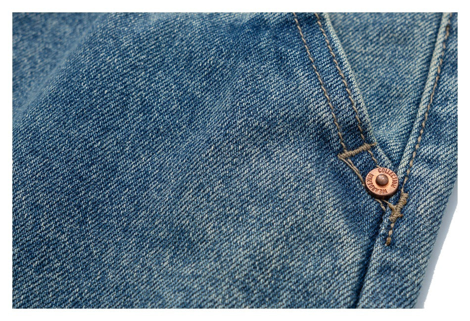 Close-up of blue denim stitching and a copper-tone rivet at a pocket corner.