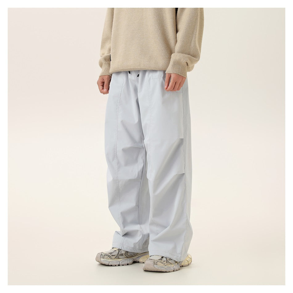 Front view of a model wearing very light gray loose pants with a large side pocket and a beige sweater.