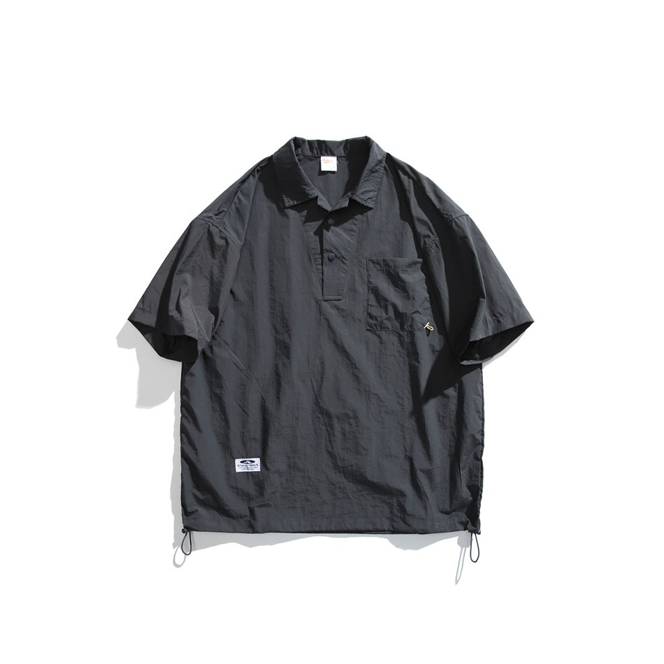 Dark gray short-sleeve pullover shirt with collar, snap placket, chest pocket and drawcord hem, flat lay
