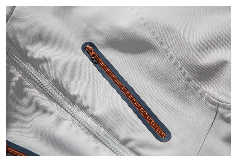 Close-up of an orange zipper with a dark trim panel on the light gray jacket.