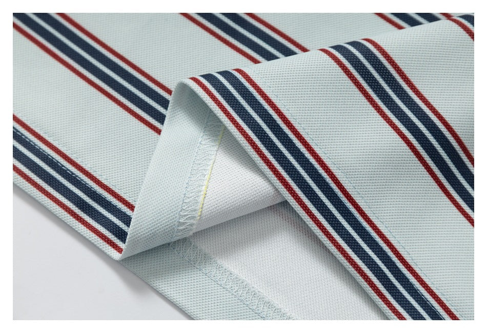 Folded edge of pale striped fabric showing the stitching and seam finish.