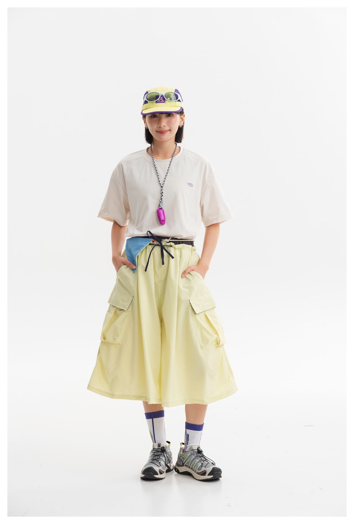 Model wearing a pale yellow flared cargo skirt with large side pockets and a drawstring waist.