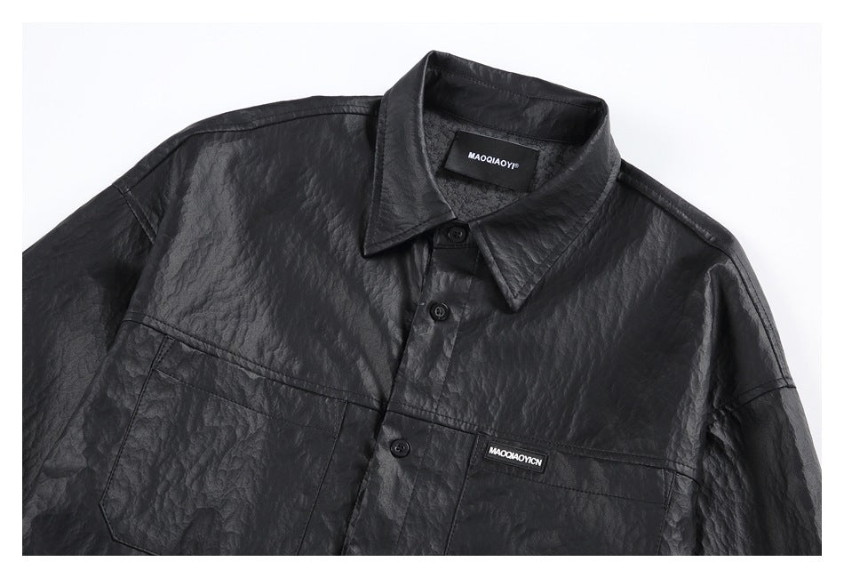 Close view of a black crinkled shirt's pointed collar, buttons, and chest pockets.