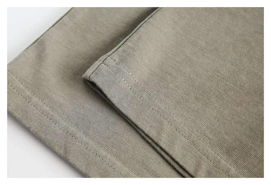 Close-up of a muted khaki garment edge showing folded fabric and parallel stitching.