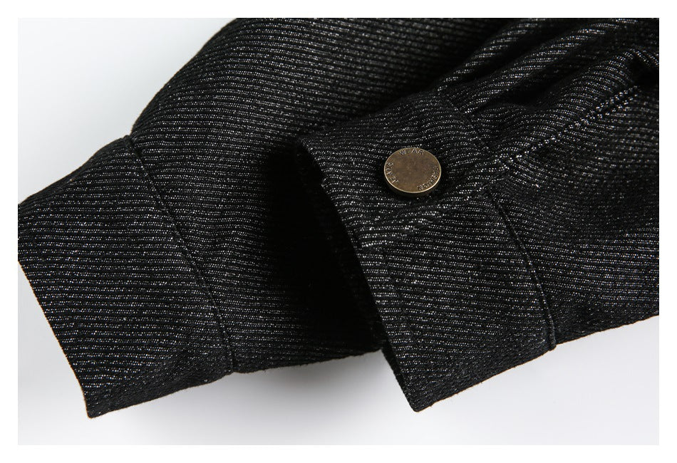 Close-up of a black denim cuff with a metal button and stitched seam.