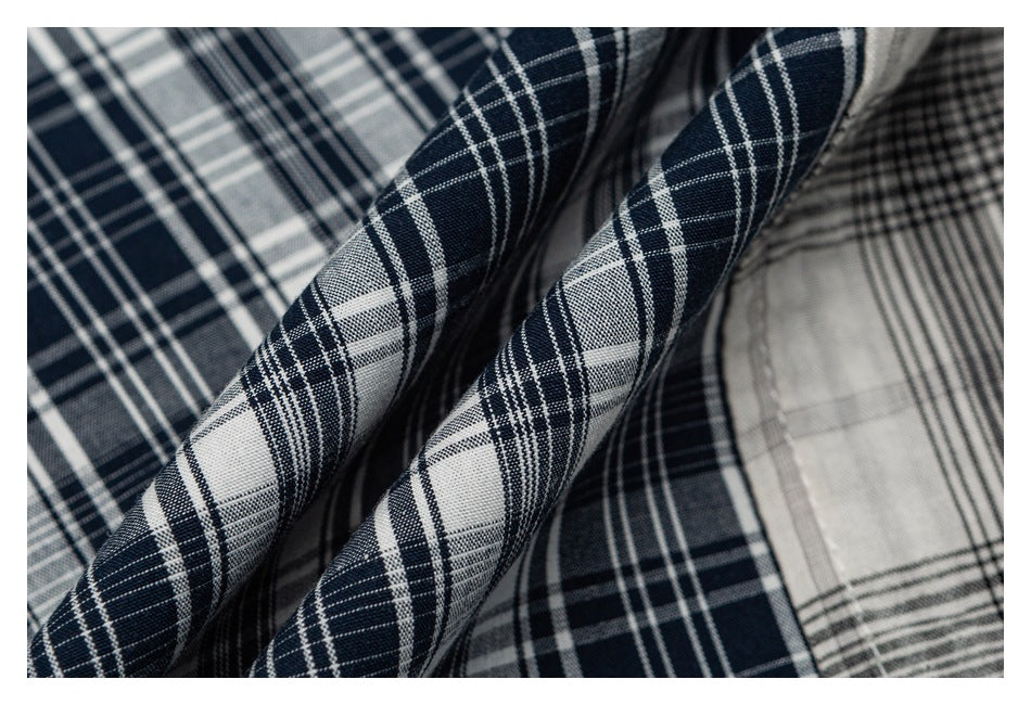 Close-up of draped navy-and-white plaid fabric with gray plaid visible beneath and beside it.
