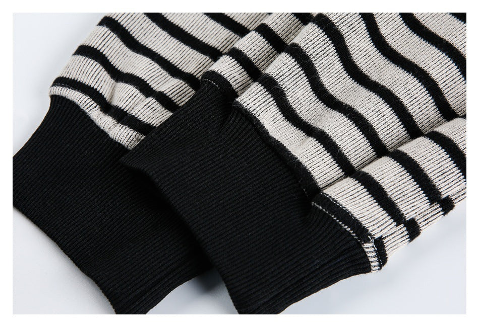 Close-up of two wide black ribbed cuffs against black-and-white striped knit sleeves.