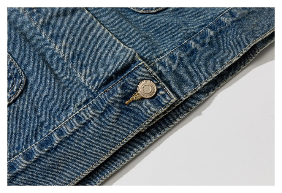 Close-up of a blue denim jacket placket and metal button against a white background.