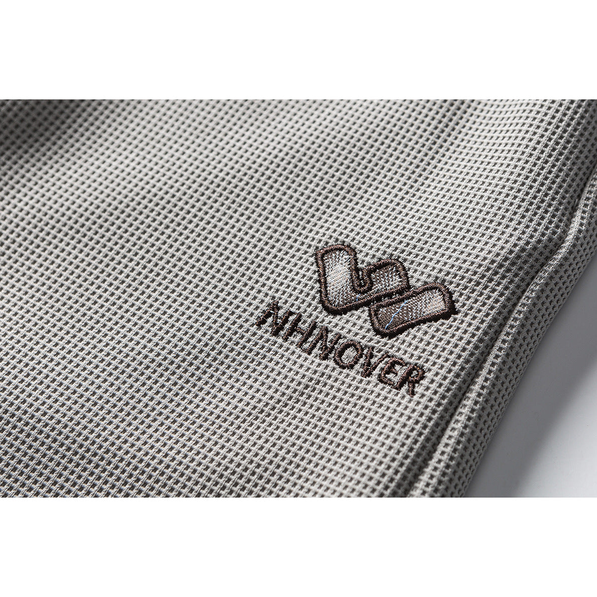 Close-up of light gray textured trousers with a small embroidered WINOVER logo.