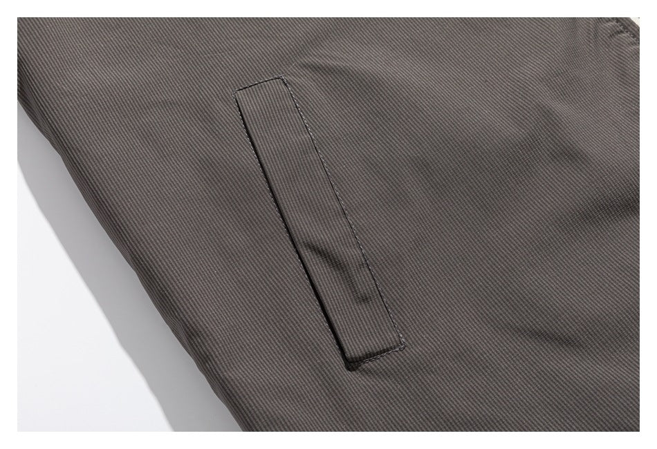 Close-up of a vertical welt pocket on the gray jacket's textured fabric.