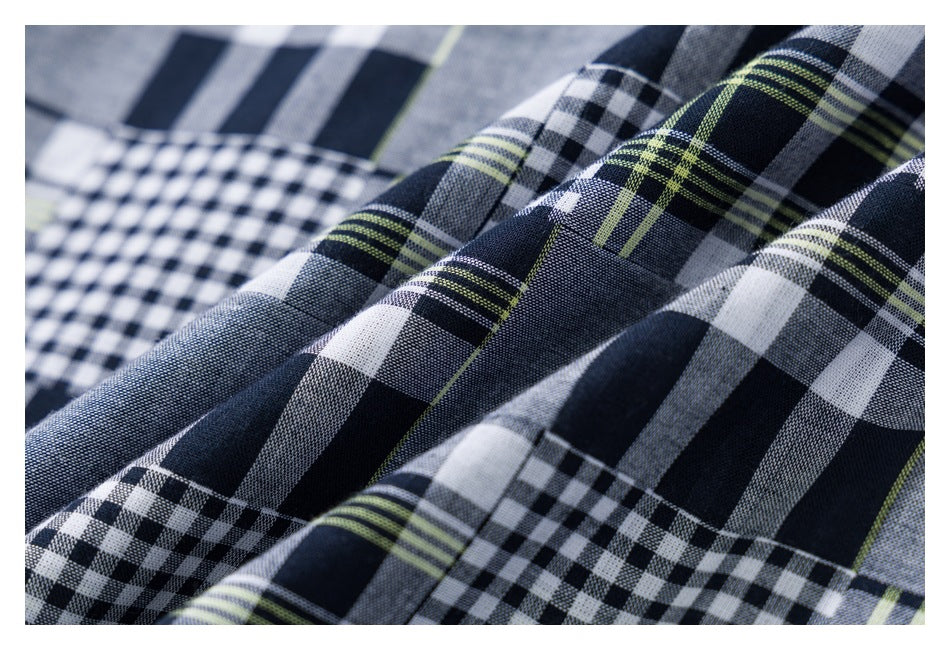 Close-up of gray, navy, white, and lime plaid fabric with alternating stripe and check patterns.