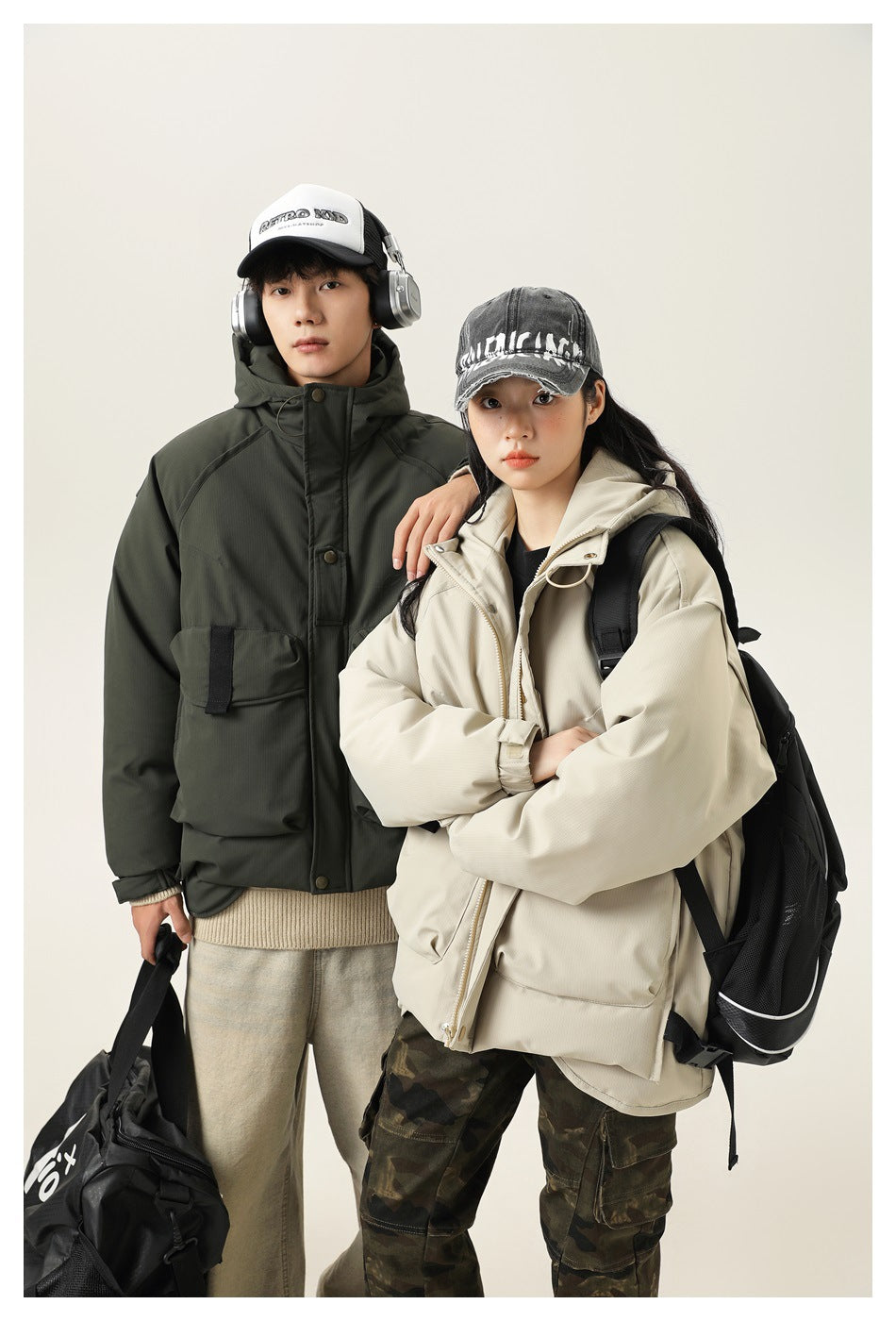 Two models wear dark olive and light beige hooded utility jackets; the beige jacket is shown with a backpack.