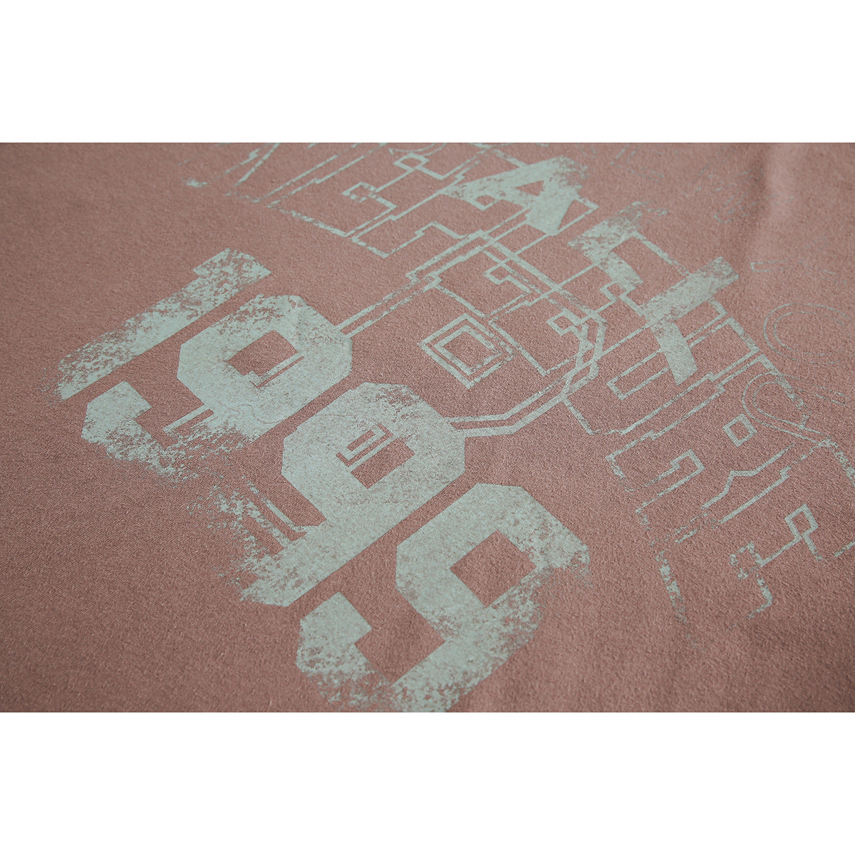Close-up of dusty rose fabric with a distressed pale mint graphic of large numerals and geometric line art.