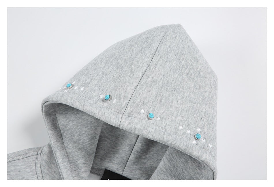 Close-up of a light gray hoodie with turquoise and white embellishments along the hood edge.