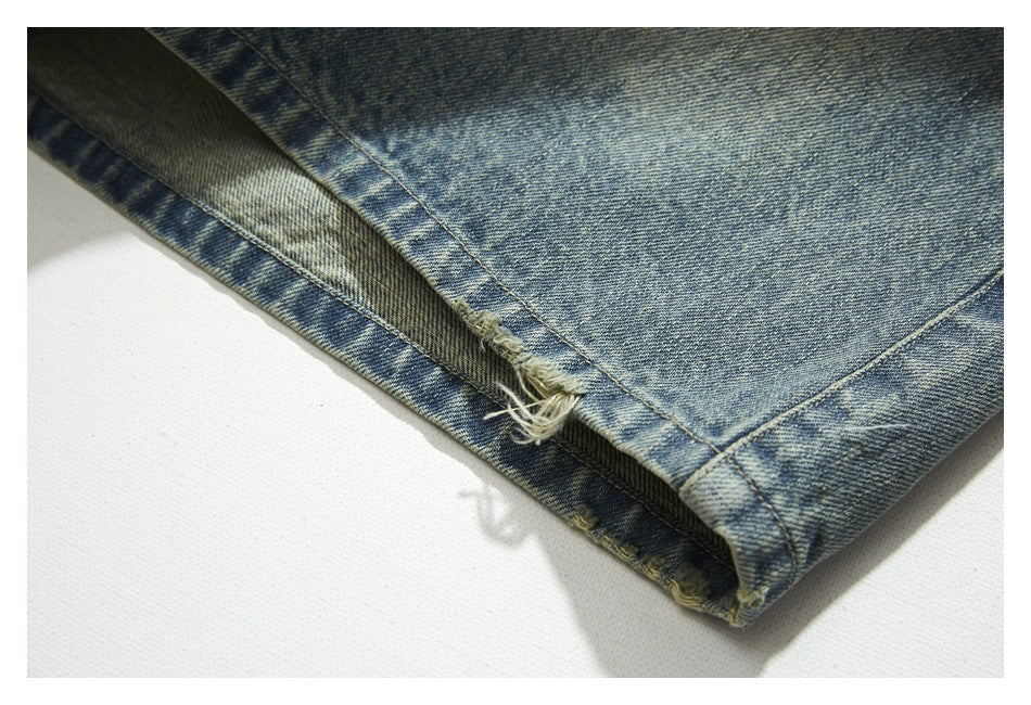 Close-up of blue denim with a frayed, worn hem edge and visible stitching.