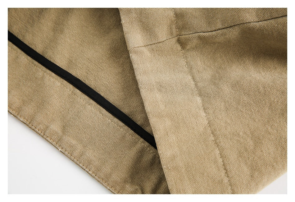 Close-up of tan jacket fabric and seams, with a strip of black trim along the edge.