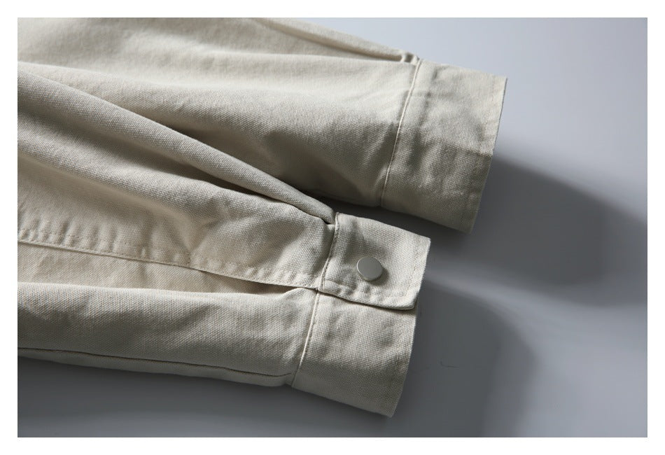 Close-up of light beige garment sleeves with wide cuffs and a silver snap button.