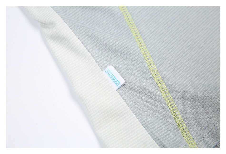 Close-up of pale gray shirt fabric and bright yellow stitching beside a small sewn-in tag.