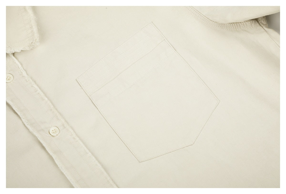 Close-up of an ivory shirt chest pocket and frayed button placket.