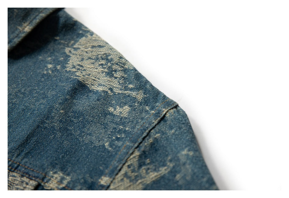 Close-up of a blue distressed denim jacket shoulder and sleeve with pale worn-pattern details.